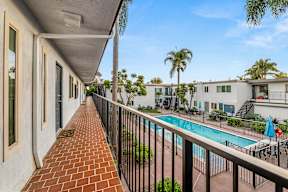 A balcony with a pool and palm trees in the background.