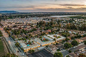 A cityscape with a mix of residential and commercial buildings, viewed from a high vantage point during sunset.
