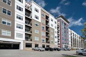 A multi-story apartment building with a parking lot at Cosmopolitan Apartments, Pittsburgh, PA