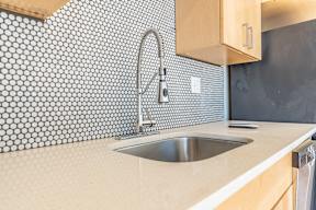 A kitchen with a sink and a tile backsplash.