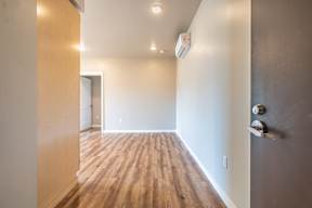 A long hallway with wood floors and a door on the right.