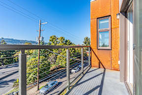 A car is parked on the street below a balcony.