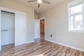 A room with a ceiling fan and wooden flooring.