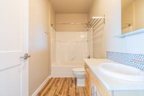 A white bathroom with a toilet, sink, and shower.