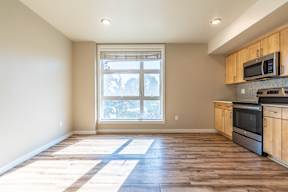 A kitchen with wooden floors and a window letting in sunlight.