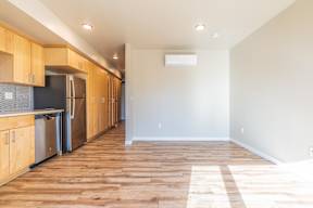 A kitchen with wooden floors and a white wall.