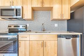 A kitchen with wooden cabinets and a black fridge.