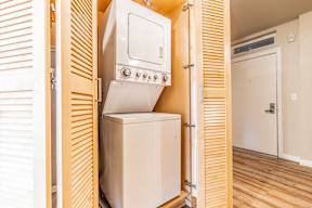 A white oven and fridge are built into a wooden cabinet.