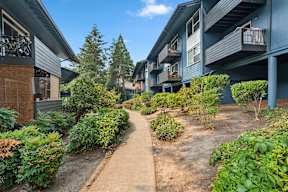 A pathway leads through a landscaped courtyard between two buildings.