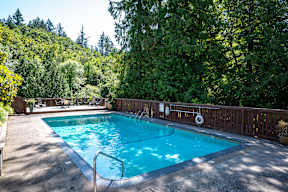 Swimming Pool With Relaxing Sundecks by a wooden fence and trees at Timberlee, Portland, OR, 97221