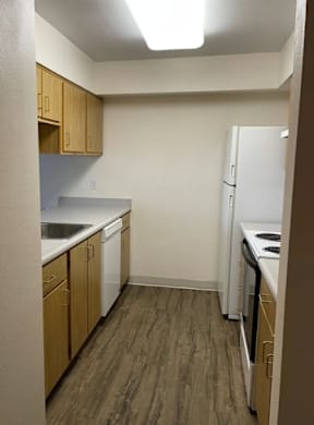 A small kitchen with a white refrigerator and wooden cabinets.