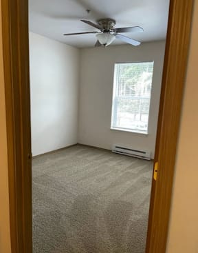 A room with a ceiling fan and a window.