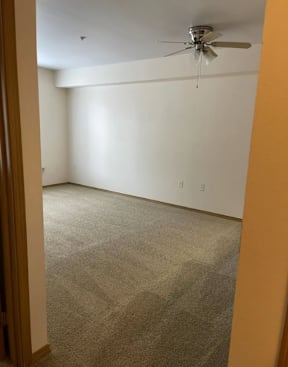 A room with a ceiling fan and carpeted floor.