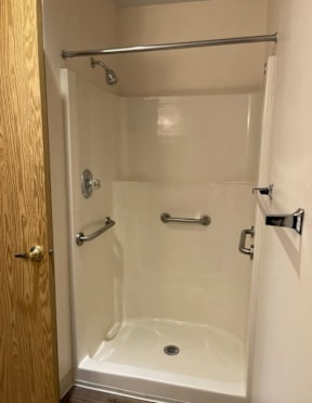 A white shower stall with a door and a shower head.
