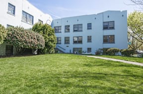 A white building with a green lawn in front.