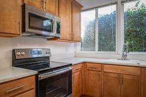 Electric kitchen with wooden cabinets and a black stove top oven at Timberlee, Portland, OR