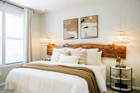 A bedroom with a large bed and two wall lamps.