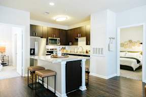 A kitchen with a black refrigerator and brown bar stools.
