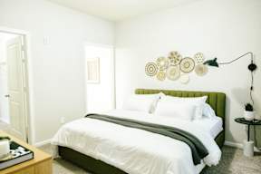 A bedroom with a bed, nightstand, and lamp.
