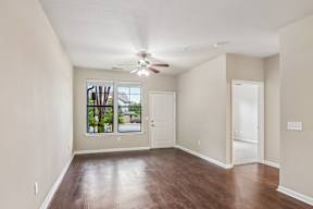 A room with a ceiling fan and a window with a view of a house.