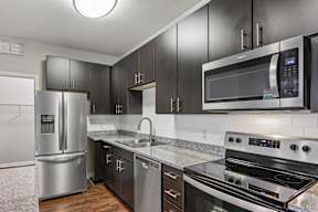 A modern kitchen with a stainless steel refrigerator, microwave, and oven.