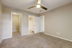 a bedroom with light colored walls and carpet and modern ceiling fan looking into a bathroom at Veridian Sandy Springs