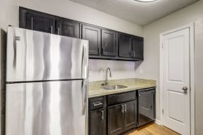 a kitchen with black cabinets and a stainless steel refrigerator