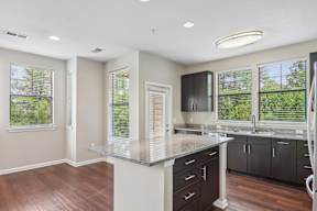 A kitchen with a large island and dark wood floors.