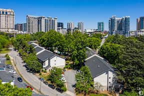 A residential area with houses and trees in the foreground and a city skyline in the background.