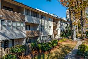 Apartment building with a clear blue sky above and trees with autumn leaves in the foreground.