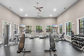 A spacious gym with a variety of equipment and windows.
