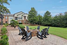 A patio with four chairs and a table in front of a house.