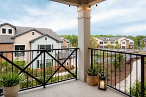 A balcony with a black railing and a lit candle on a table.