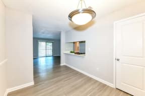 an empty living room with a kitchen in the background