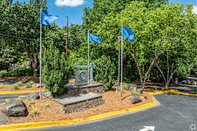 A sign with the letter C on it is surrounded by blue flags and trees.