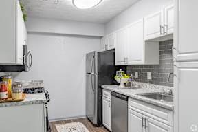 A kitchen with white cabinets and a black refrigerator.