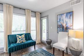 A living room with a blue couch and a painting on the wall.