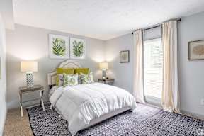 A bedroom with a large bed and two lamps.