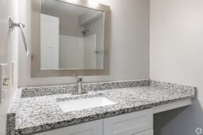A bathroom with a granite countertop and a large mirror.