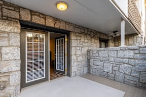 A stone wall with a doorway and a window with blinds.