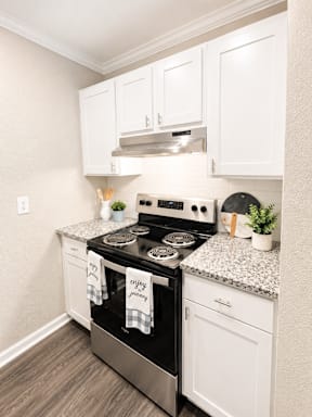 A kitchen with a stove top oven and white cabinets.