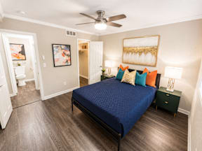 A bedroom with a blue bedspread and a ceiling fan.