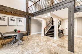 A dining room with a table and chairs and a staircase.