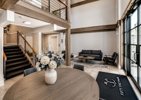 A modern living room with a staircase and a dining table.