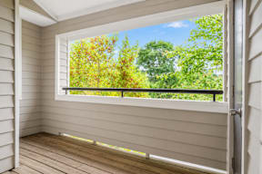 A room with a window overlooking a green landscape.
