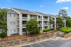 A row of apartment buildings with a parking lot in front.