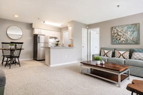 A modern kitchen with a refrigerator, sink, and a dining table with chairs.