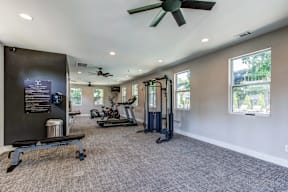 A spacious gym with a variety of equipment including a treadmill, a stationary bike, a rowing machine, and a bench press.