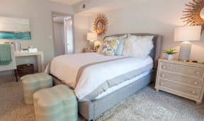 A bedroom with a large bed, a nightstand, and a dresser.