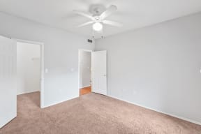 a bedroom with gray carpet and a white ceiling fan